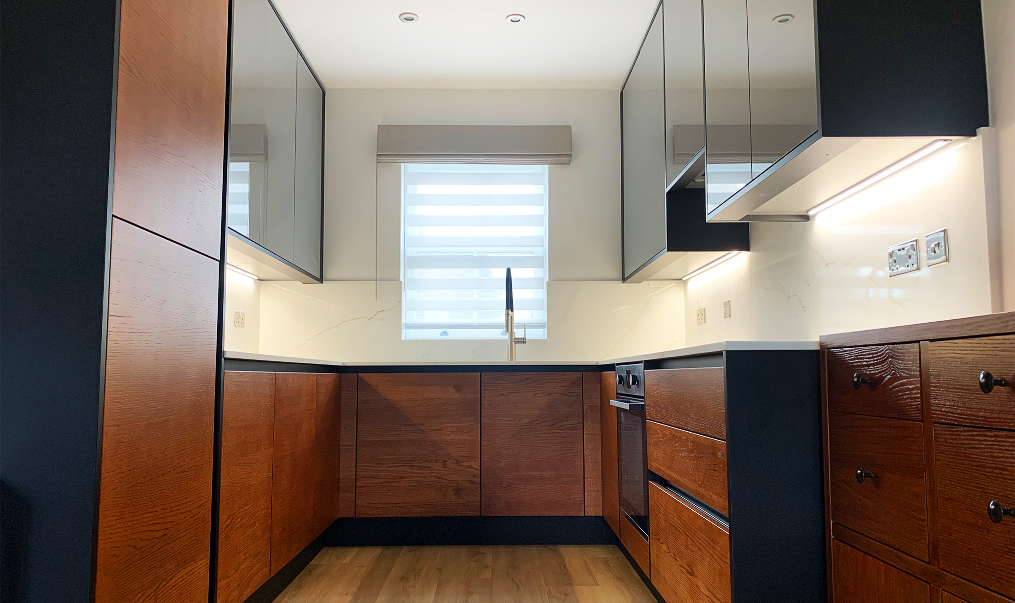 A sophisticated dark wood kitchen with sleek matt black accents, marrying elegance with modern design. Explore the perfect blend of timeless warmth and contemporary style.